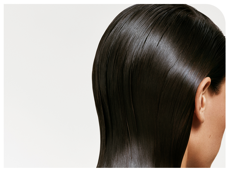 Close-up view of straight, glossy dark hair cascading down against white background, showing smooth and sleek texture.