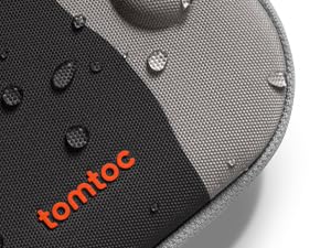 Detail shot of orange watch strap or band with black buckle attachment against gray textile surface.