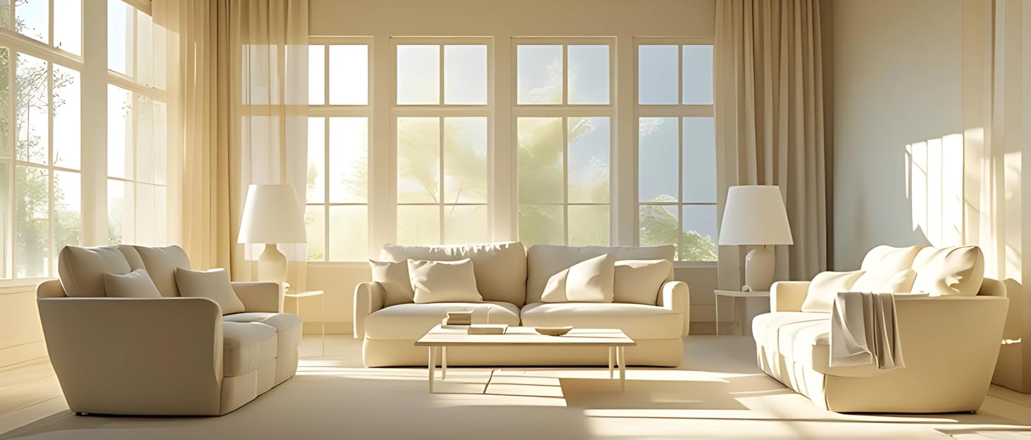 Sunlit living room with beige furniture set including sofa, armchairs, and coffee table. Large windows with sheer curtains provide natural light and outdoor view.