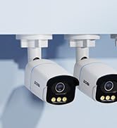 Security camera system with four white bullet cameras and a black rectangular network video recorder. Cameras feature visible LEDs and adjustable mounts.