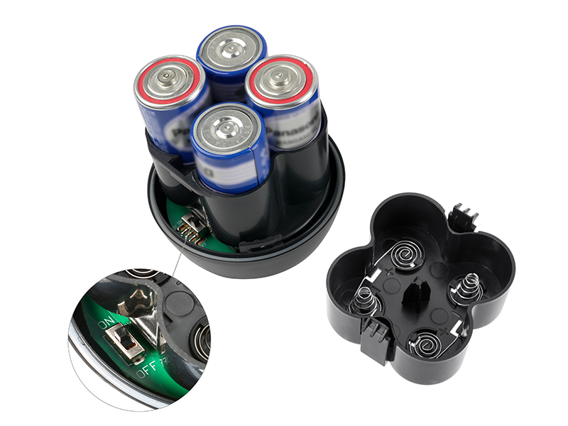 Black plastic battery compartment holder showing assembled and disassembled views, designed to hold four cylindrical batteries in a circular arrangement.