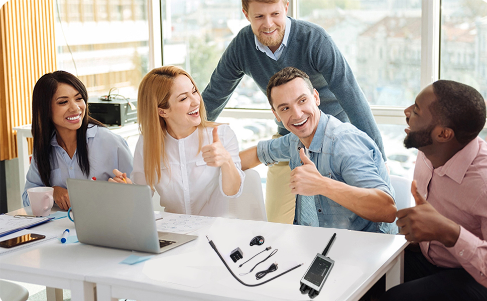 a group of people sitting around a table with a laptop and a cell phone.