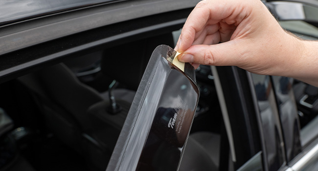 Close-up of a car window with visible water droplets or rain on the glass and window trim.