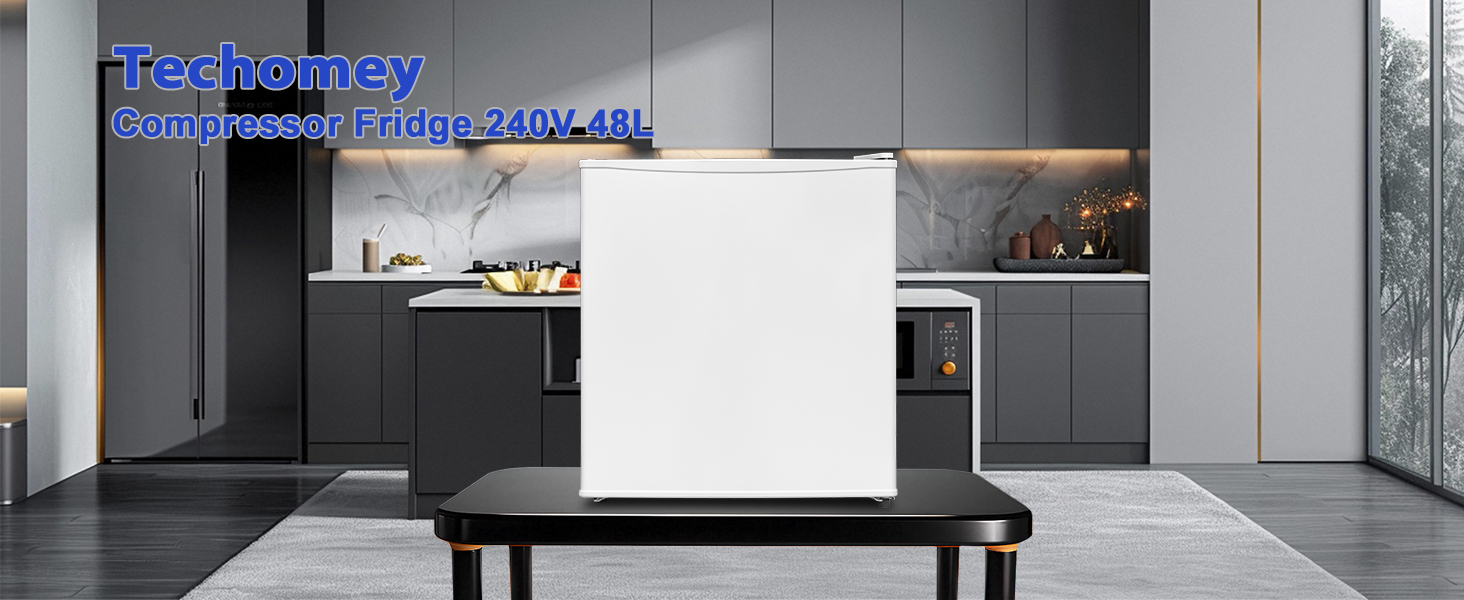 Modern kitchen interior featuring grey cabinetry and white surfaces, with central island or table in foreground.