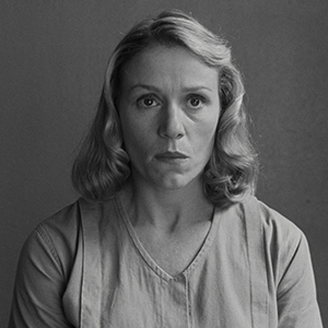 Black and white vintage-style portrait photograph showing subject in light-colored clothing against neutral background.