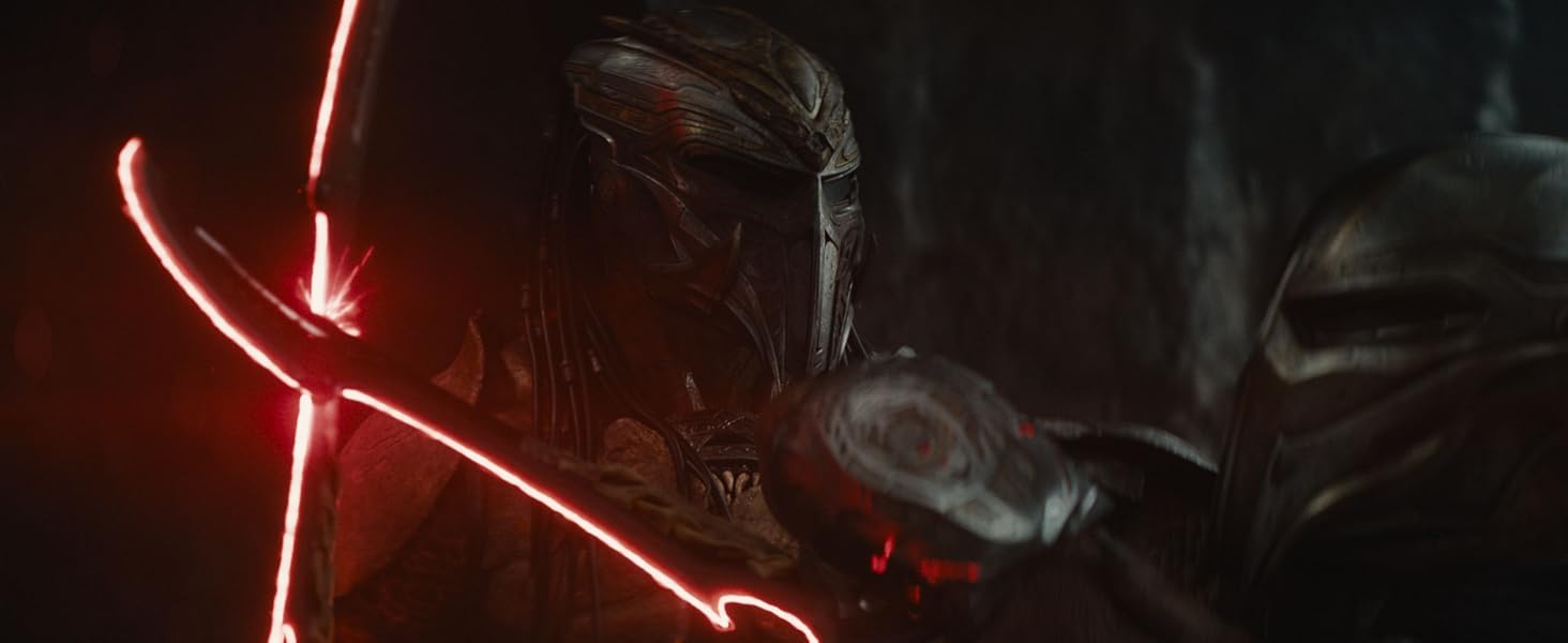 Two individuals in what appears to be a film or cinematic scene, positioned close together against a soft-focused natural background.