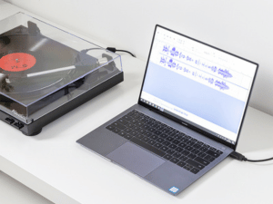 Close-up view of a turntable playing a vinyl record, showing the platter, tonearm, and orange and yellow record adapters visible in the frame.