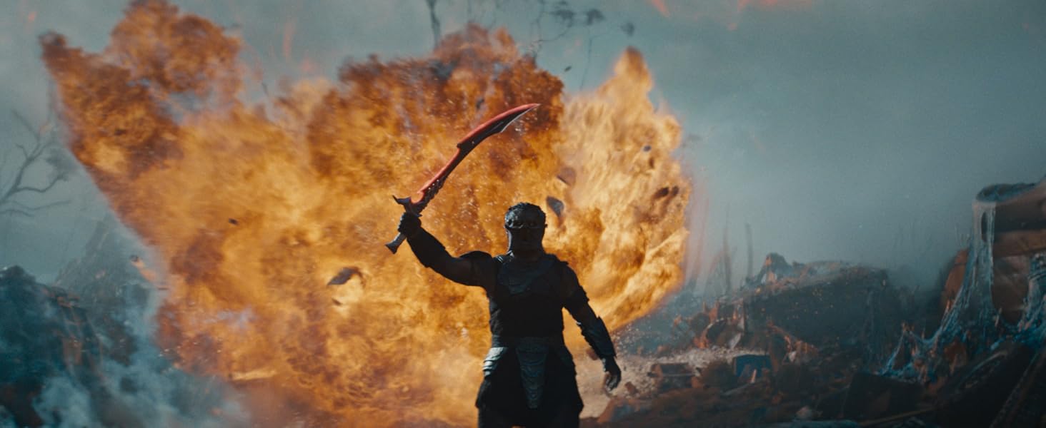 Action sequence showing silhouettes against large orange flame explosions in dramatic outdoor scene.