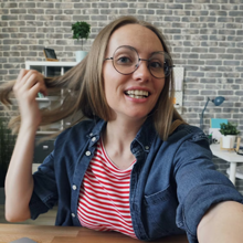 First-person view from bicycle handlebars showing sunny path ahead with trees and blue sky visible in the distance.