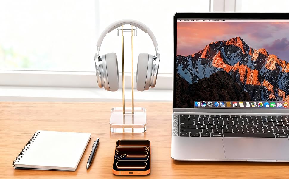 Clean, minimalist desk setup with Apple MacBook, white desk accessories, and office supplies arranged neatly against light wooden surface.
