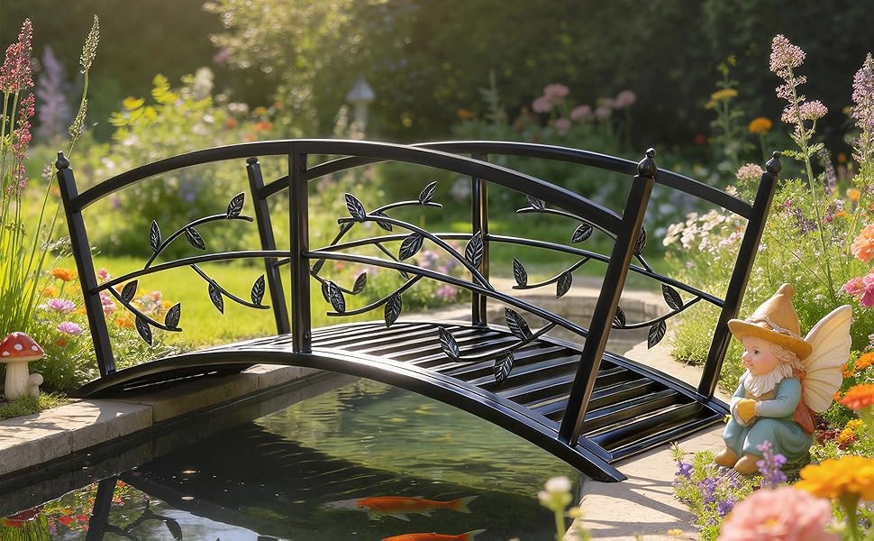 Decorative garden bridge with arched metal railings, spanning over landscaped area with colorful flowers and greenery.