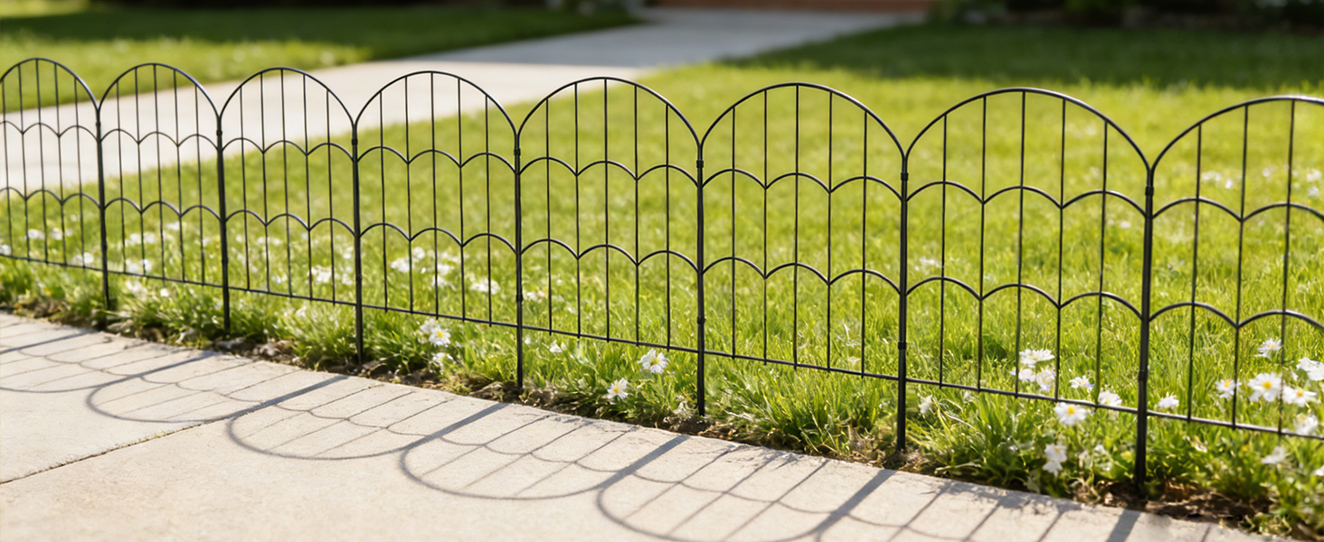 Decorative metal garden fencing panels installed on grass, featuring curved archway designs and black metal construction.