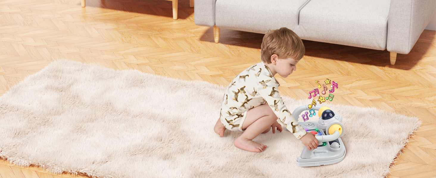 Infant in patterned outfit playing with colorful activity toys on white sheepskin rug on wooden floor.