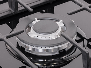 Close-up of gas stovetop burner with metallic control knob and circular flame ring on black stovetop surface.