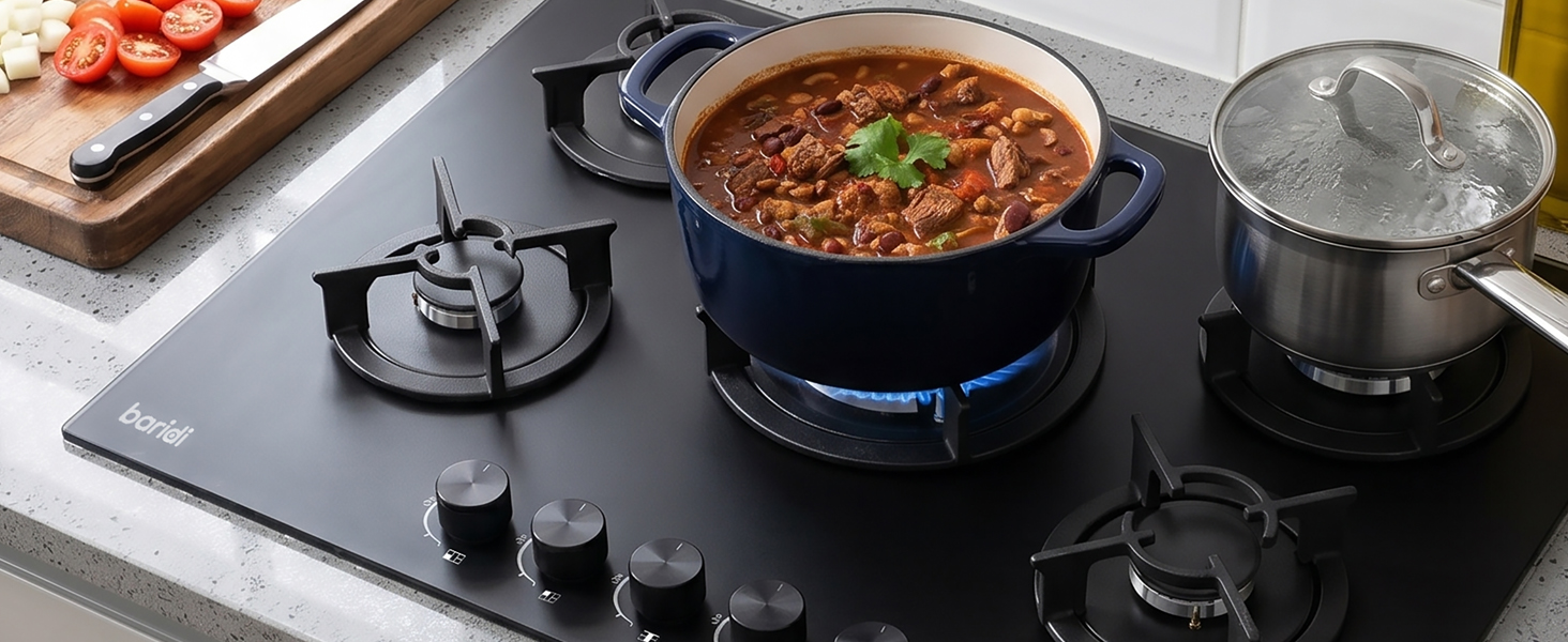 Portable induction cooktop with black surface on white countertop. Cooking demonstration showing pot with red sauce, stainless steel pot, and cutting board with food ingredients.