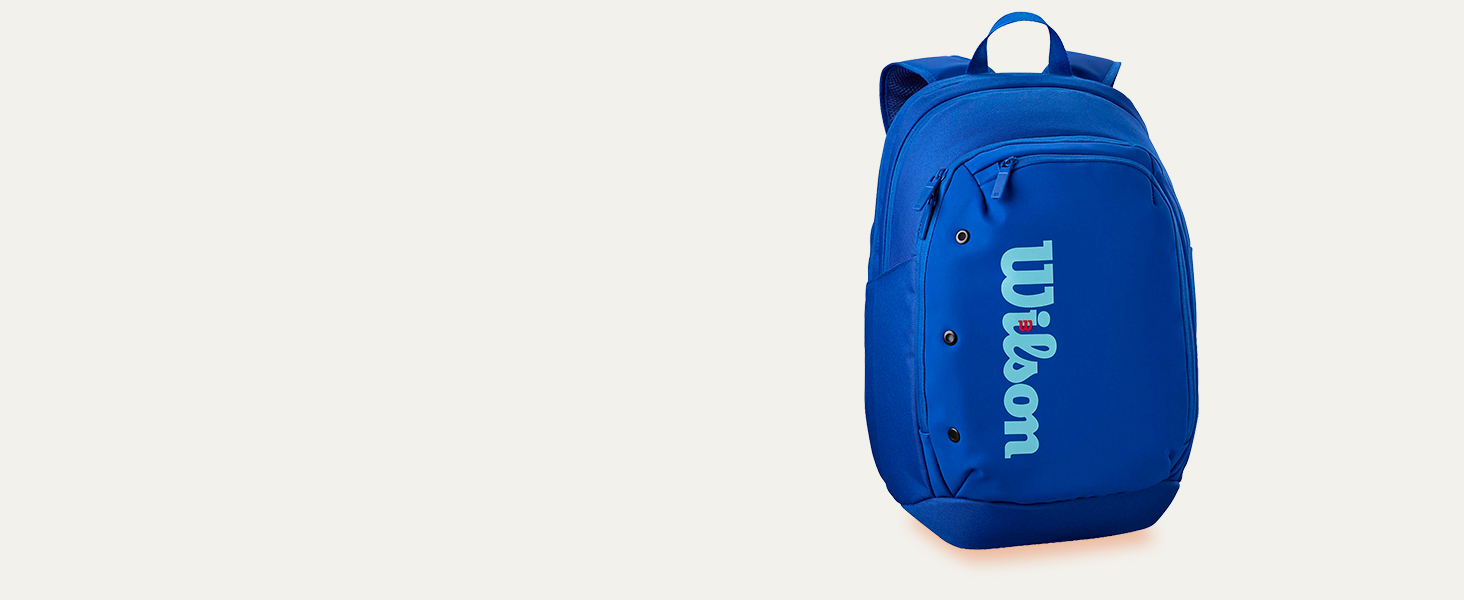 Text reads 'wilson' on blue backpack. Cobalt blue athletic daypack with carry handle and brand logo on front.