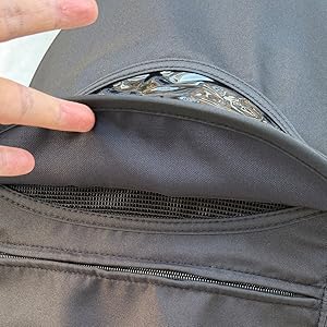 Black zippered storage pouch with dual compartments attached to white and black backpack frame, showing organizational pocket design.
