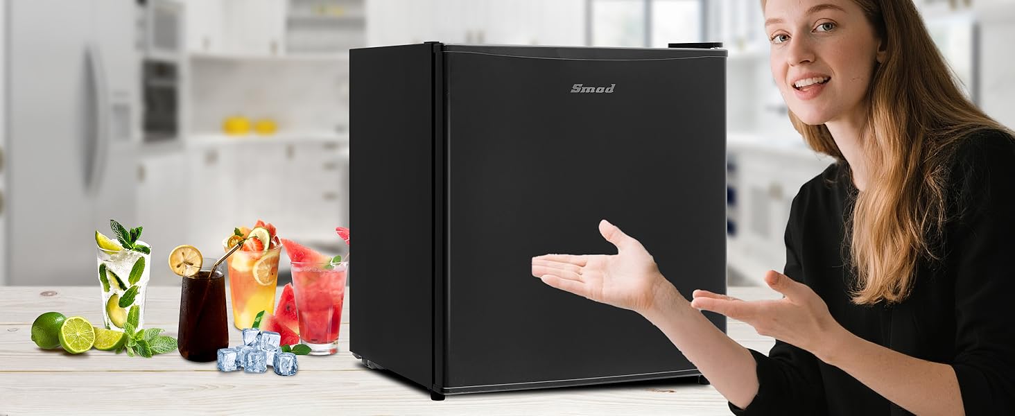 Compact black mini refrigerator shown in kitchen setting with decorative elements on top. Demonstrative product presentation showing size and placement.
