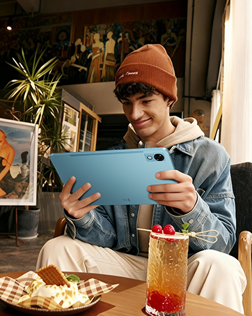 Person in light blue shirt holding and displaying a turquoise/cyan colored laptop computer against white background.
