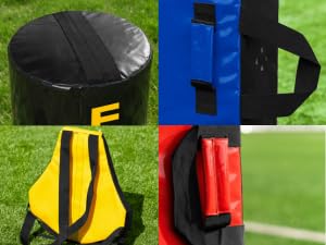 Text reads: 'FORZA' on multiple yellow sports training equipment pieces. Yellow fitness gear including tires, resistance bands, and cylindrical training tools with 'FORZA' branding, displayed on grass with trees and blue sky background.