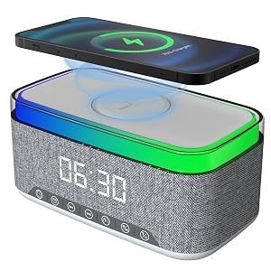 Text reads '06:30'. Bluetooth speaker with gray fabric body, green trim, and digital clock display with smartphone wireless charging pad mounted on top.