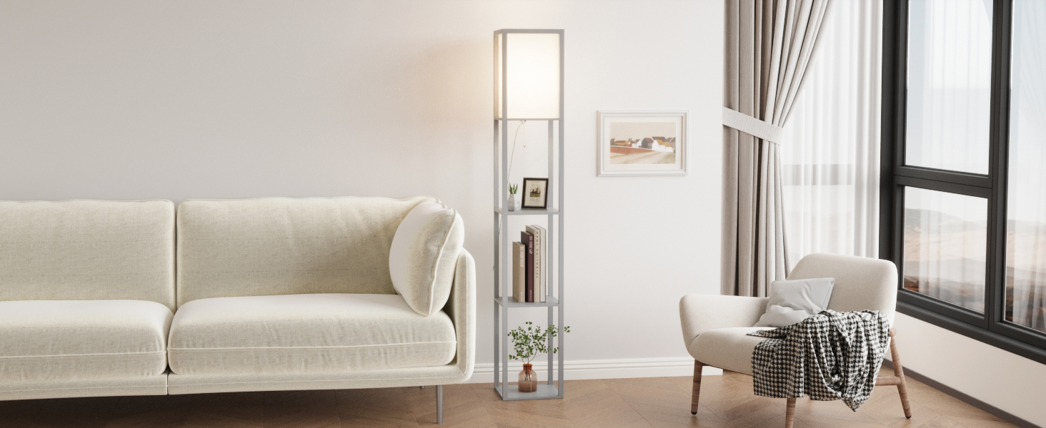 Living room with white sofa, armchair, and throw blanket. Window with curtains, standing lamp, and framed artwork visible. Neutral color scheme with white brick wall.