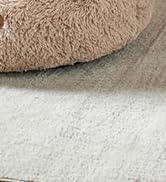 Close-up product photo showing brown rounded object on a light textured surface.