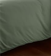 Close-up of sage green pillow against vertical slatted headboard or wall panel.