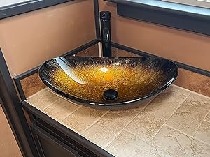 Two illuminated glass vessel sinks on a granite countertop. Sinks have a golden-yellow glow and black faucets mounted behind them.