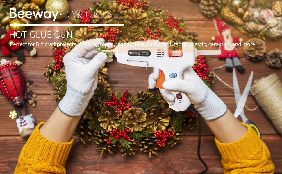 woman holding a hot glue gun over a christmas wreath
