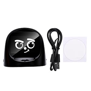 Black dome-shaped device with smiling face design, featuring two round eyes and curved smile. Includes coiled black power cable and white circular disc pad in packaging display.