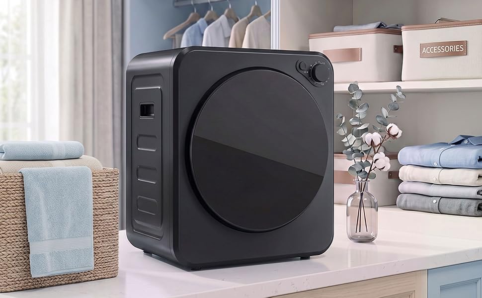 Black compact washer/dryer unit displayed on white desk with stacked linens, decorative vase, and home storage shelving in background.