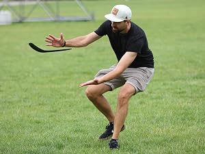 Person performing athletic stretching or warm-up exercise on grass field, demonstrating flexibility and sports training movement.