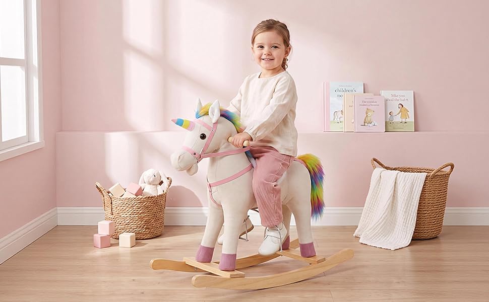 Child in beige sweater sitting on pink and white wooden rocking horse toy in bright room with storage baskets and clothing rack visible.