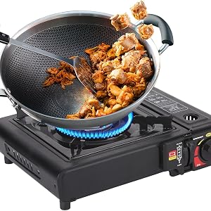 Black portable induction cooktop with wok-style cooking pan containing stir-fried food on burner, power adjustment knob visible, heating element glowing blue underneath.