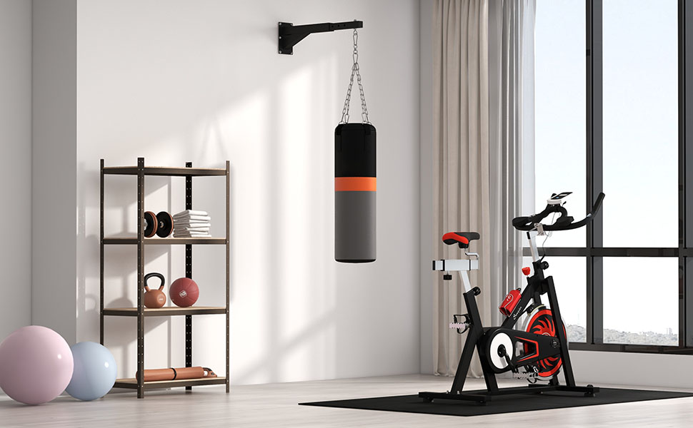 Interior home gym setup displaying wall-mounted shelving unit with decorative items, hanging punching bag, exercise bike, exercise ball, and tall window with curtains in minimalist modern space.