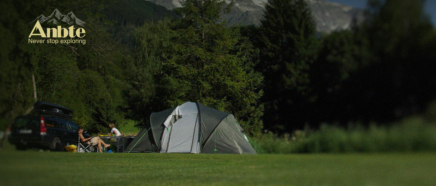 Nighttime camping scene with illuminated tents in a forested area. 'Anble' logo visible in the top left corner.