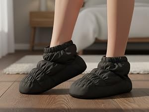 Pair of black quilted puffy slippers or bootie-style footwear with gathered elastic ankle cuffs and cushioned construction.